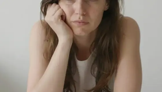A young woman named Ibolya with a confused expression, surrounded by numerous colorful buttons scattered around her, in a simple indoor setting with soft lighting, realistic human features, no text or letters visible