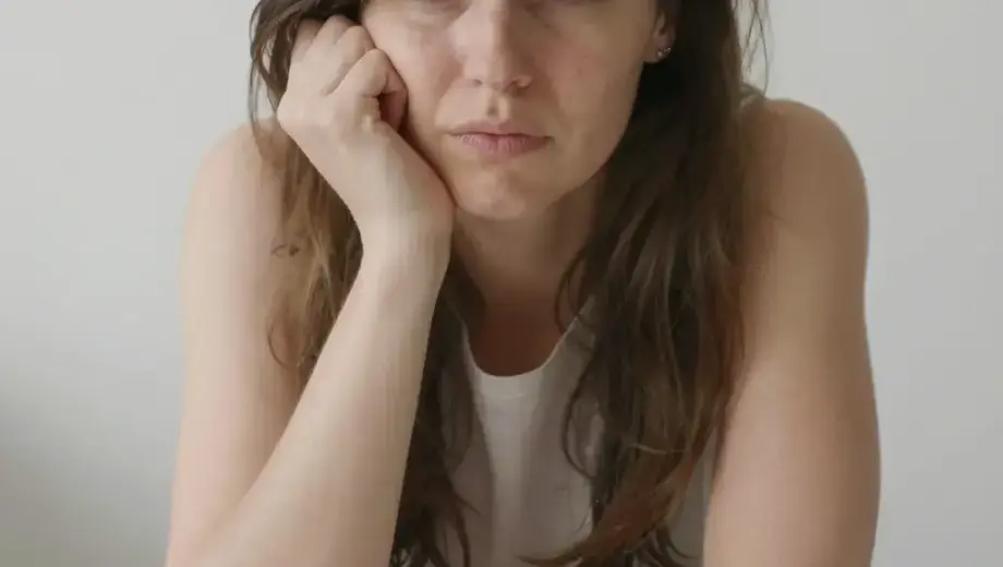 A young woman named Ibolya with a confused expression, surrounded by numerous colorful buttons scattered around her, in a simple indoor setting with soft lighting, realistic human features, no text or letters visible