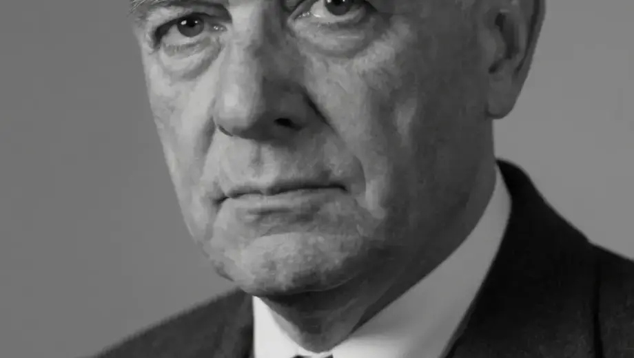 A somber black and white portrait of a 68-year-old man, László Varga, with a serious expression, looking slightly to the side, wearing formal attire from the mid-20th century, soft lighting, high detail, emotional atmosphere, subtle grain texture