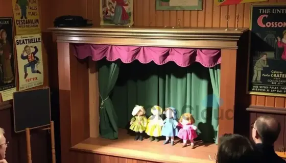 Interior of a small, cozy Hungarian puppet theater (Csodamalom Bábszínház) in Miskolc, showing a wooden stage with colorful puppet figures, warm lighting, audience seating, and vintage posters on the walls, capturing the atmosphere of the 2016-17 season in February