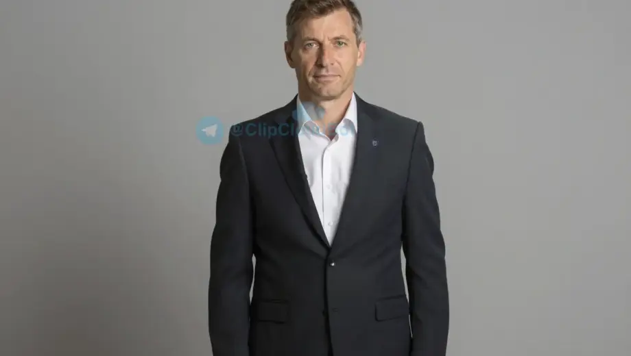 A formal portrait of a Hungarian sports patron (mecénás) from 2017, dressed in a classic suit with a subtle sports emblem on the lapel, standing in a dignified pose against a neutral background, conveying support for sports development