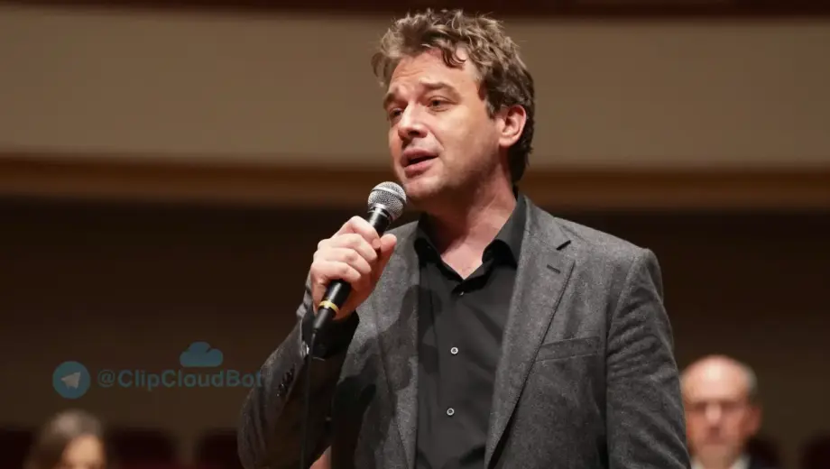 A portrait of János Elek Mészáros performing on stage at a concert in Miskolc, holding a microphone, with warm stage lighting, a subtle background of a concert hall with blurred audience and musical instruments, expressing emotion through his singing, realistic details in clothing and facial expression