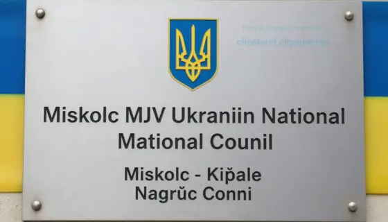 A formal commemorative plaque or sign for the Miskolc MJV Ukrainian National Council, featuring official text in Hungarian and Ukrainian, with the emblem of the Ukrainian National Council, set against a dignified background with national symbols like the Ukrainian flag colors and possibly the coat of arms of Miskolc, in a clear, respectful, and official style