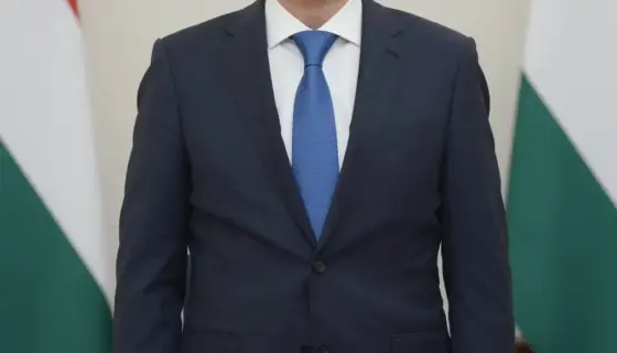 A formal portrait of a middle-aged Hungarian man in a suit, standing in a dignified pose with a serious expression, set against a classic office background with a wooden desk and a Hungarian flag in the corner, conveying respect and authority