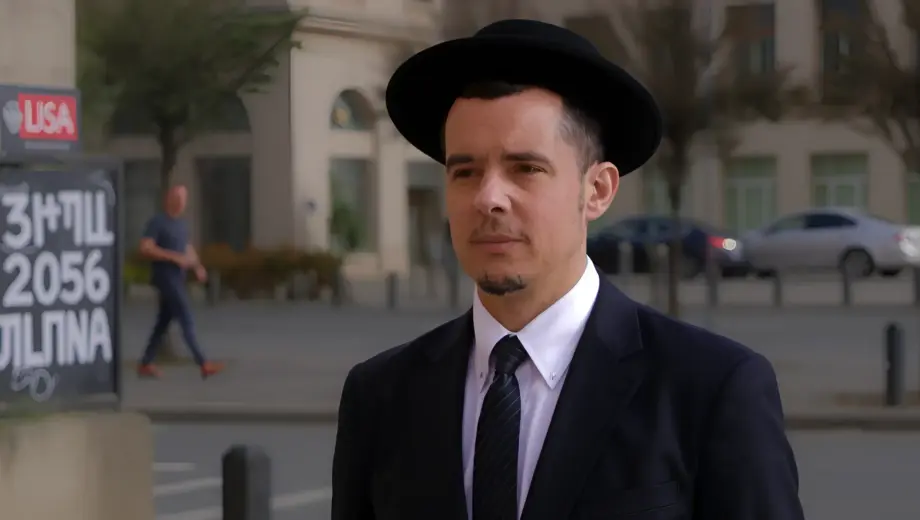 A solemn Jewish man in traditional attire (kippah, suit) standing in a modern German city square, with subtle antisemitic graffiti on a nearby wall, muted colors, serious expression, photorealistic detail