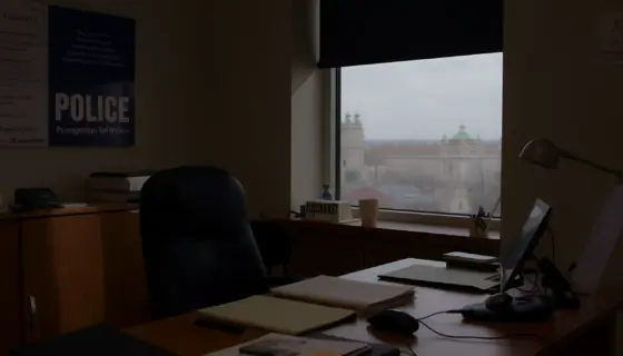 A police captain's office in a Hungarian police station, featuring a desk with official documents, a badge, a radio, and a window showing a cityscape, realistic lighting and details