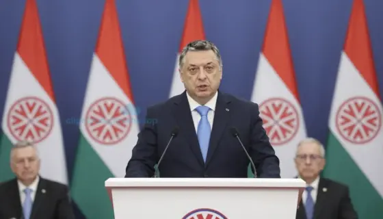 Prime Minister Viktor Orbán speaking at a Fidesz party congress, standing at a podium with Hungarian flags and party banners behind him, audience of supporters in the background, formal political setting, dignified expression