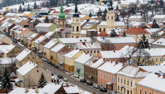 A vibrant and detailed scene showcasing the city of Miskolc and its surrounding area during the winter season. The image should capture the essence of the region, including its architecture, natural landscapes, and cultural elements. Snow-covered streets, traditional buildings, and local landmarks should be prominently featured. The atmosphere should be warm and inviting, highlighting the beauty of Miskolc in winter.