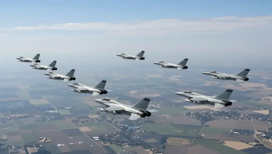 Aerial view of a large-scale military operation with approximately one hundred Israeli fighter jets flying in formation over a distant landscape, targeting long-range objectives. The scene should depict the jets in mid-flight, showcasing their precision and coordination. The background should include a clear sky with some clouds, and the distant landscape should be visible but not detailed, emphasizing the vast distance the jets are covering.