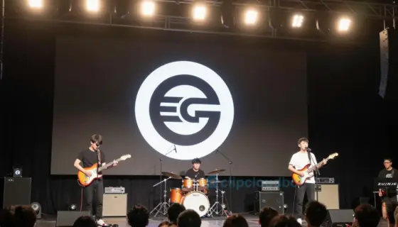 A concert stage with a band performing, featuring a prominent Egr logo or symbol, warm stage lighting, audience in the background, and a clear indication of a Thursday event