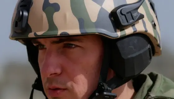 A close-up, high-resolution shot of an Israeli soldier wearing a distinctive, modern combat helmet with a unique camouflage pattern and integrated communication gear. The soldier's face is partially visible, showing a focused expression. The background is a blurred, neutral military setting to emphasize the subject. The image should be photorealistic and detailed, suitable for a news article or feature story.