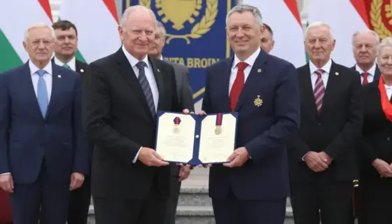A formal ceremony in Borsod-Abaúj-Zemplén, Hungary, where local residents receive official state honors, with dignitaries presenting certificates or medals in a grand hall or outdoor plaza, Hungarian flags and official banners visible, people in formal attire smiling and receiving awards, diverse group of adults and elders, dignified and celebratory atmosphere