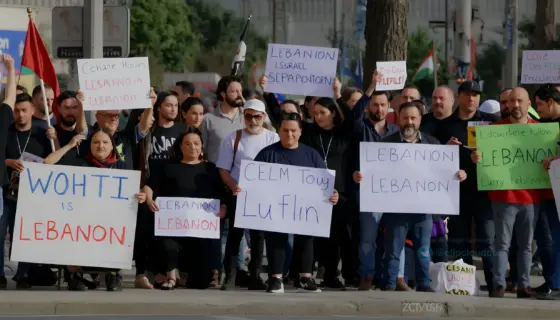 A tense protest scene in Palestine featuring diverse demonstrators holding signs against terrorism organizations, set against a backdrop of urban streets with subtle references to Lebanon and Israel, rendered in a realistic style emphasizing emotional intensity and political context