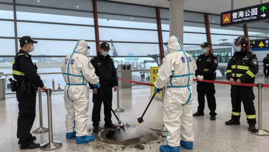 A dramatic scene at an airport terminal showing emergency responders in protective gear containing a gas leak, with a detained individual in custody nearby, and security personnel implementing safety measures such as barriers and evacuation signs, all under bright airport lighting with visible aircraft in the background through glass walls